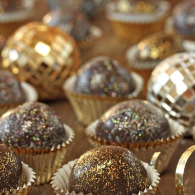 Sparkling chocolate disco ball truffles with gold glitter beside miniature mirrored disco balls for Foodie Kids New Year's Eve cooking camp